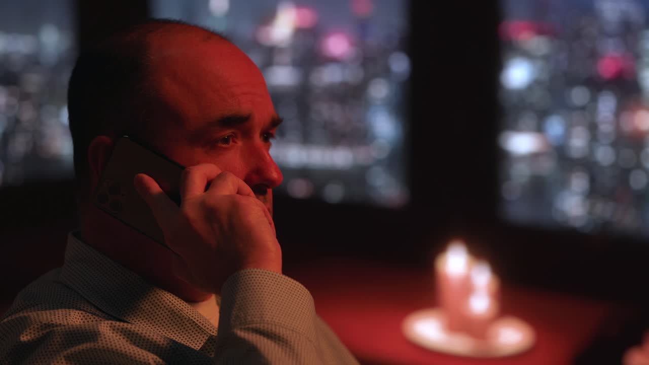 hombre blanco de mediana edad mirando por la ventana por teléfono