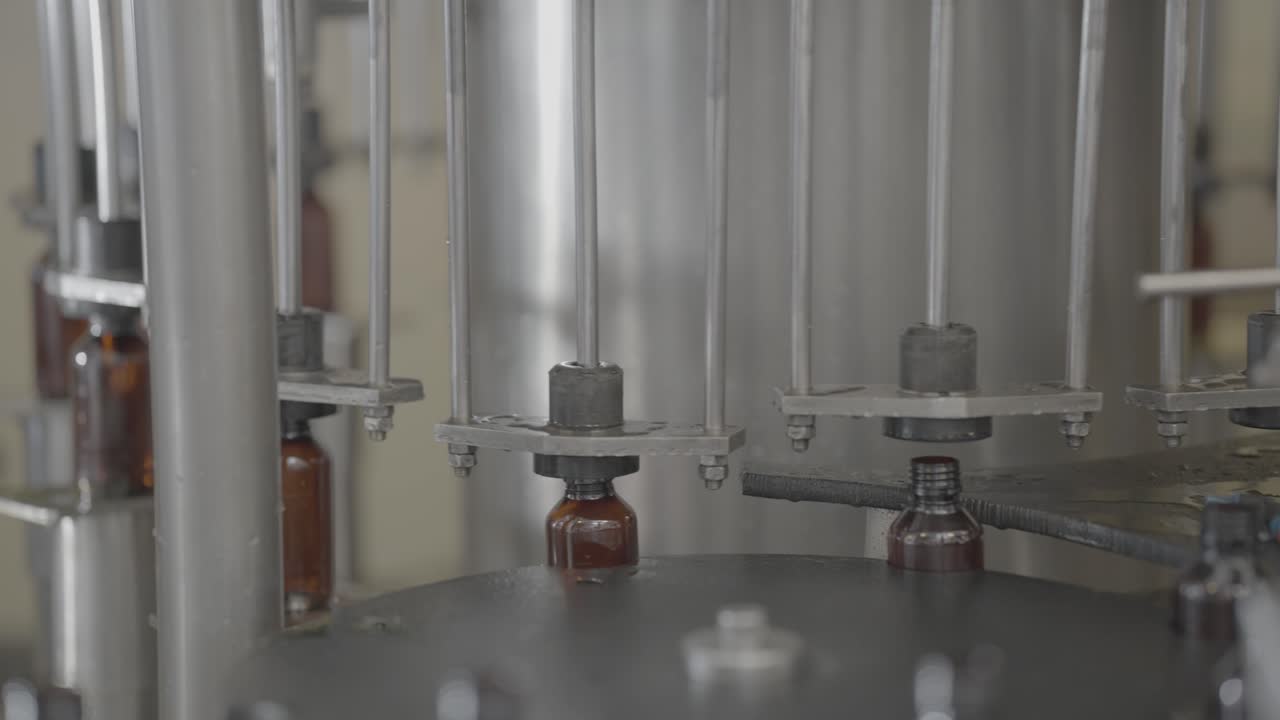 Syrup Bottles getting filled with liquid medicine in automatic machine slog footage.