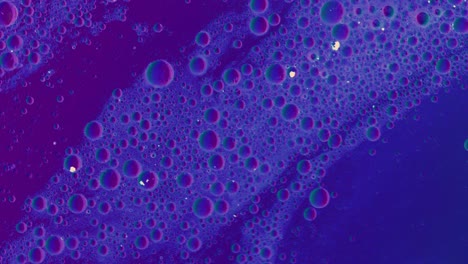 purple greasy liquid flows over a surface with bubbles and dirt