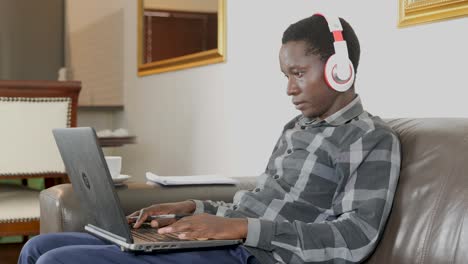 african man working from couch at home