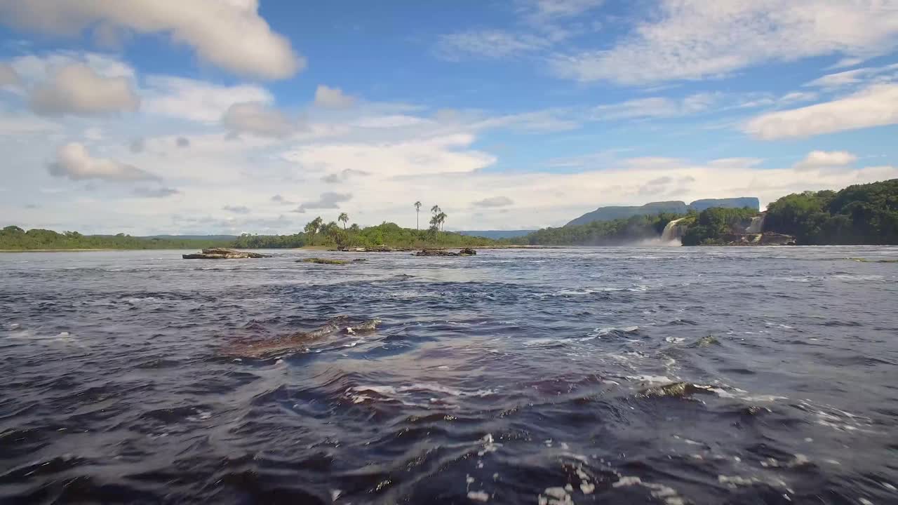 toma aerea a ras de la superficie del agua, en la laguna de canaima, con hermosos cielos y cascadas