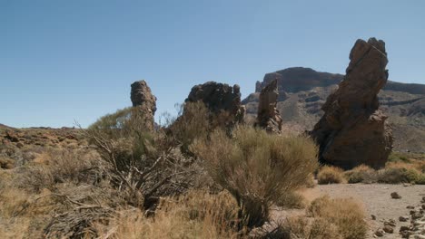 Rocas-Volcánicas-Erosionadas-Con-Arbustos-Del-Desierto-En-Primer-Plano,-Los-Roques-De-García,-Parque-Nacional-Del-Teide-En-Tenerife,-Islas-Canarias-En-Primavera