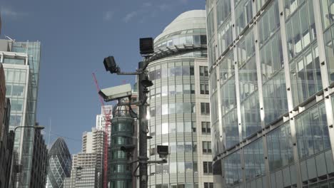 close up shot of cctv cameras in london with sunlight reflections on the windows of tall buildings