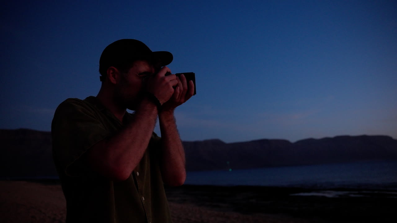 Fotografo che scatta una foto sulla spiaggia al tramonto a Lanzarote, Spagna