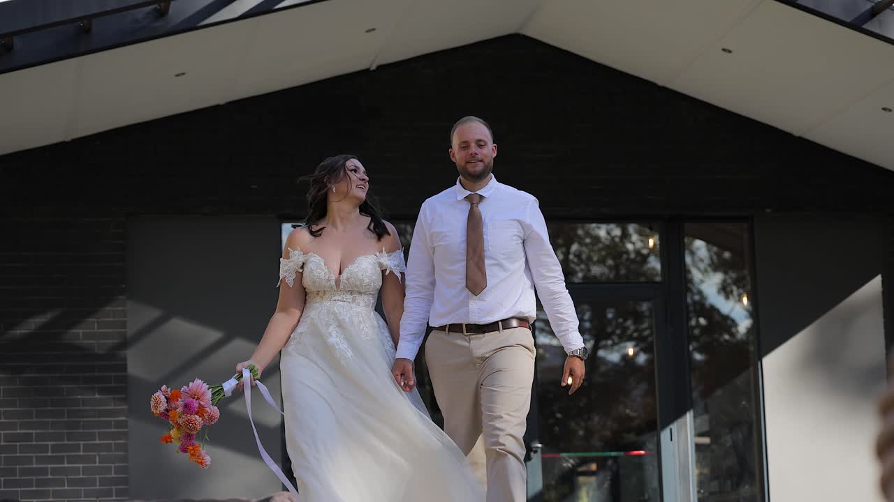 Novios alegres emergen y celebran fuera de la capilla de bodas.