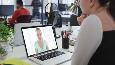 Caucasian-woman-having-a-video-call-with-male-and-female-office-colleague-on-laptop-at-office