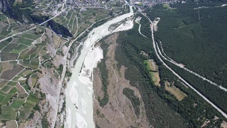 drone-shot of the rhone river flowing through the valley of valais in switzerland