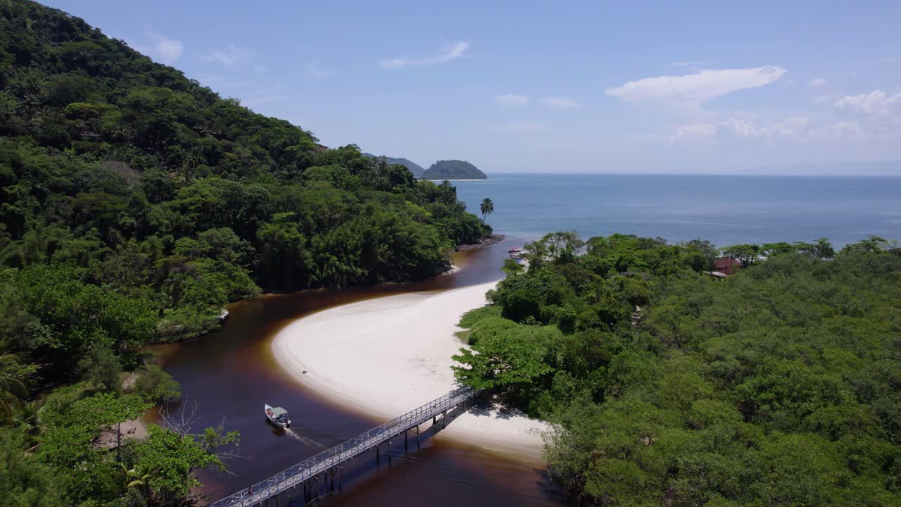 vista aérea de un barco conduciendo por el río sahy hacia el mar en el soleado brasil