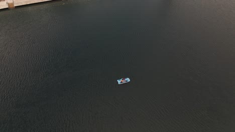 Aerial shot of people in a paddle boat on a green lake
