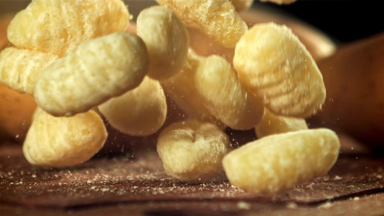 Gnocchi freschi che cadono su una superficie di legno al rallentatore