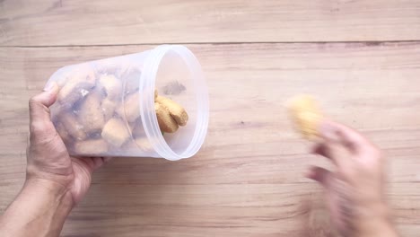 hands taking cookies from a plastic container on a wooden table