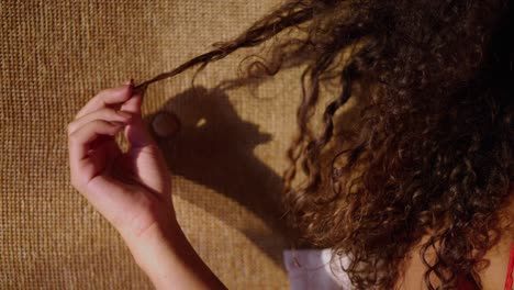 close-up of a person's hand playing with curly brown hair