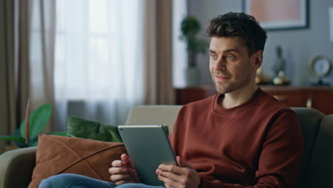 Handsome hipster shopping online using tablet at home close up. Man touching pad