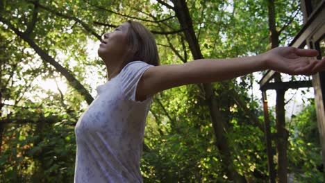 mujer asiática de pie con los brazos abiertos en el jardín y sonriendo