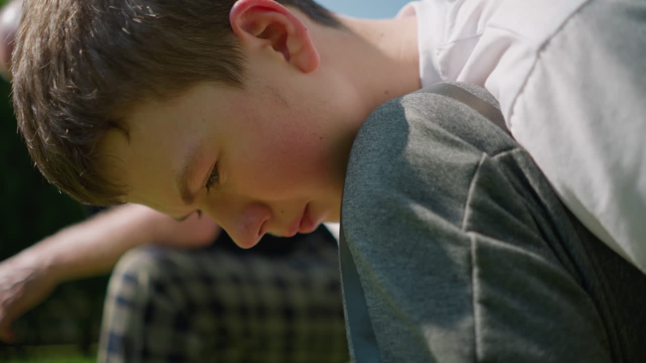 어린 소년은 무을 고 무언가에 집중적으로 일하며, 근처에 앉아 있는 할아버지의 흐릿한 시야를 가지고 있습니다.