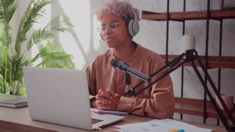 smiling african woman wearing wireless headphones preparing to record podcast