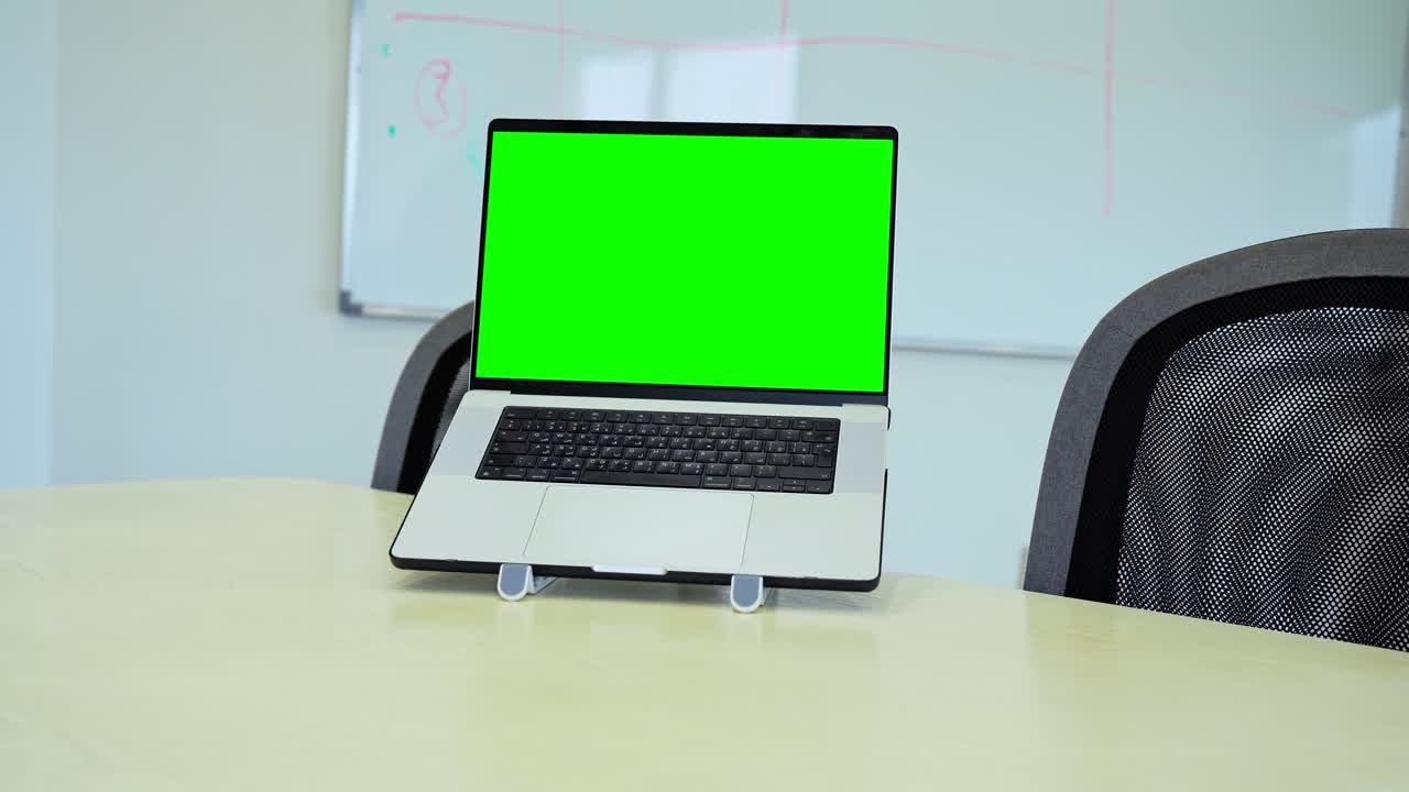 Laptop on white stand with chroma green screen in office—perfect for mockups, templates, or tech demos.