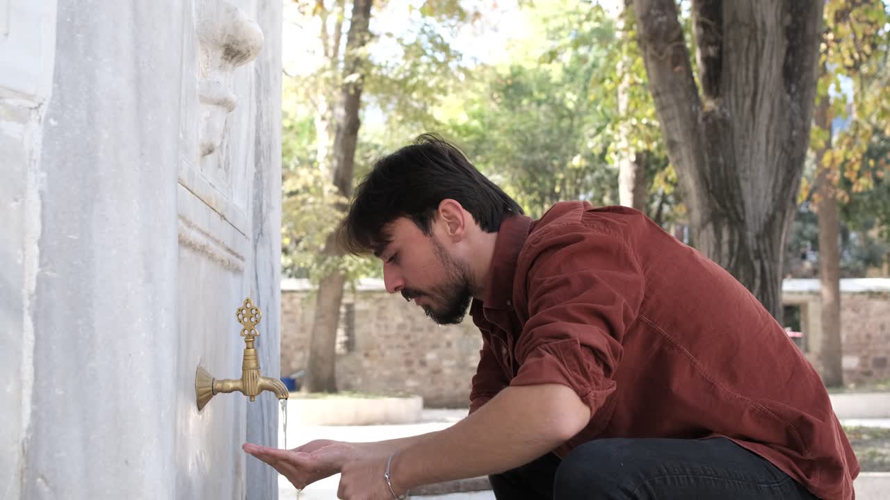 Side view of a Muslim bearded man performing ablution, a man washing his nose in a mosque fountain, cleanliness is half of faith