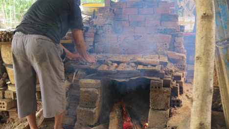 Potter-arranges-clay-figurines-ontop-fire-fed-kiln-in-Than-Ha-village-Vietnam-Hoi-An