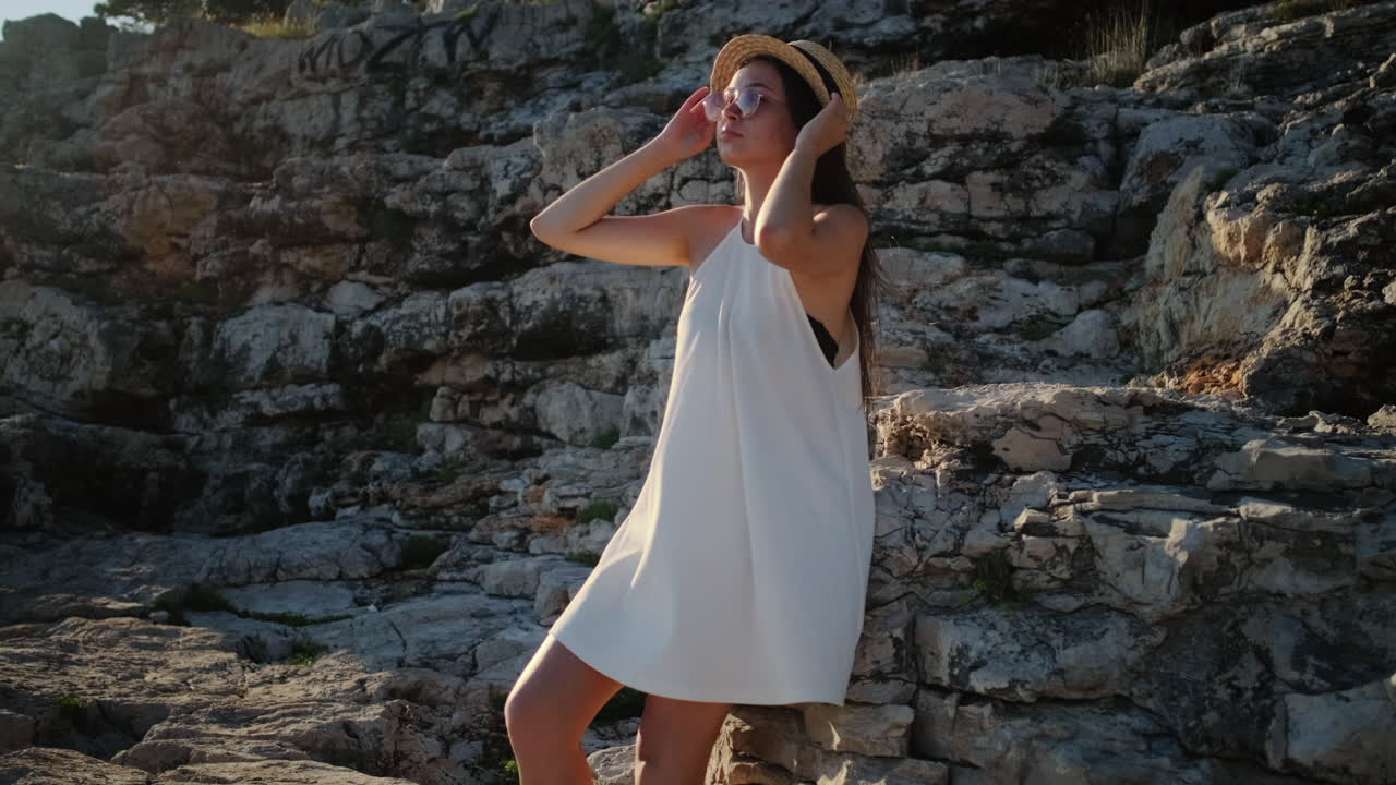 mujer con un vestido blanco en un acantilado rocoso