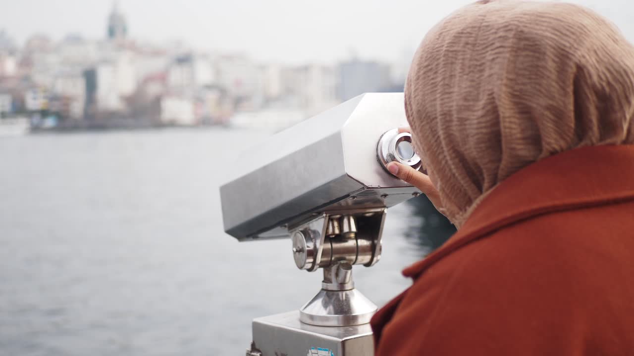 히자브 를 입은 여자 가 도시 의 스카이 라인 을 안고 있는 안경