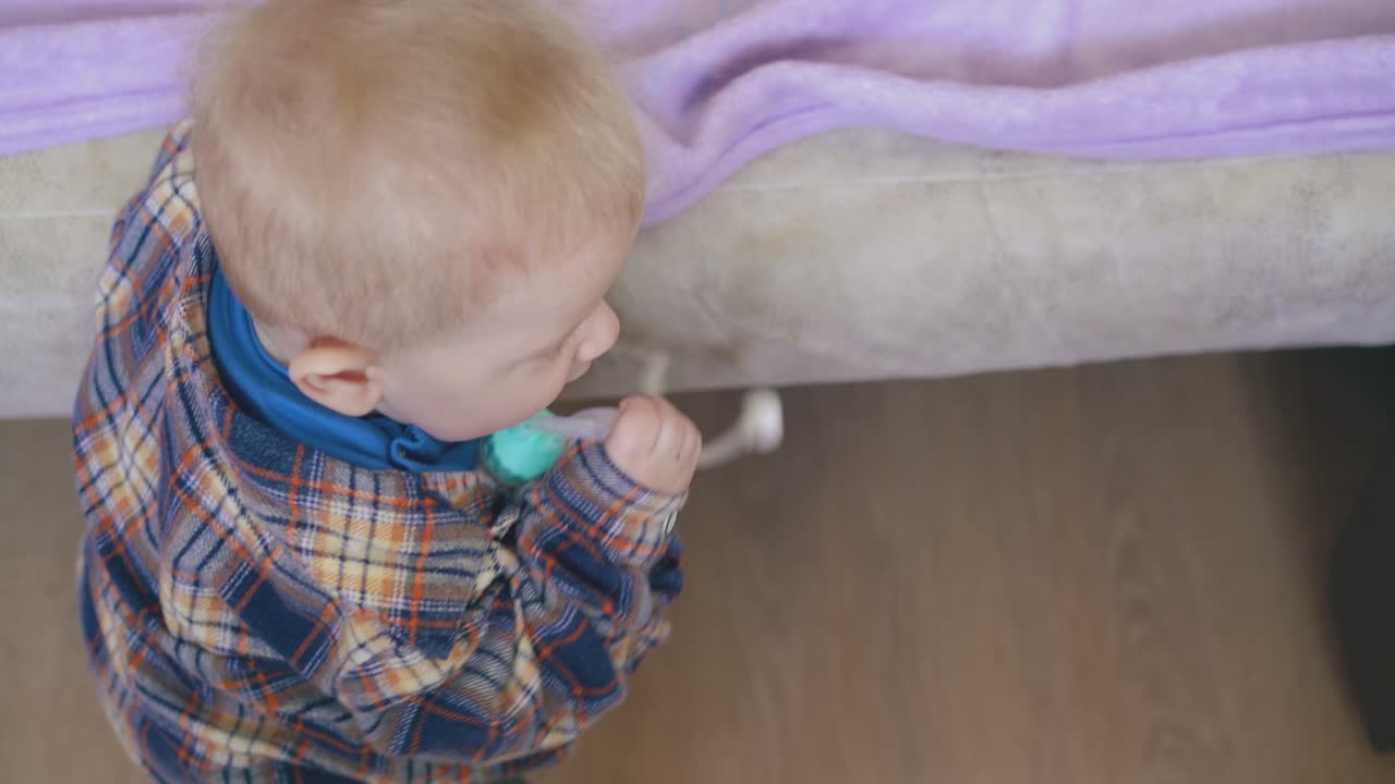 아기는 위에서 볼 수 있는 방에서 침대에서 흡입기와 함께 놀고 있습니다.