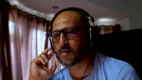 hombre del sur de asia con gafas y auriculares disfrutando de música en el interior