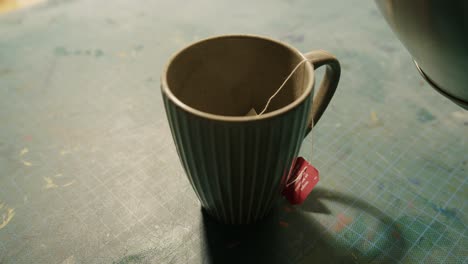 teabag being covered with hot water in a cup