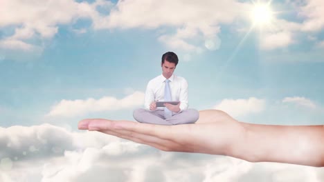Hand-holding-sitting-businessman-focused-on-tablet-computer-against-blue-sky