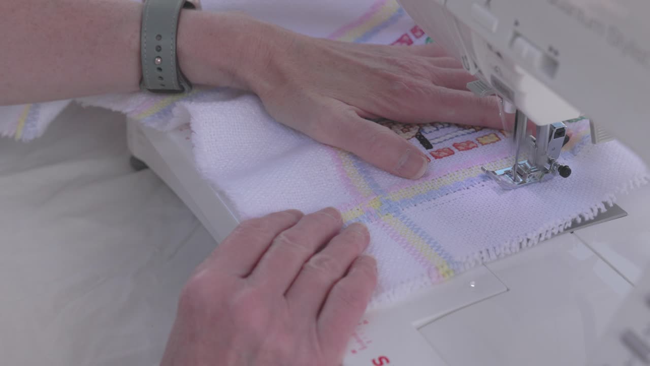 close-up shot of a seamstress using a sewing machine to finish stitching a blanket