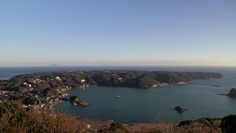 Wide-open-panoramic-view-high-above,-looking-out-on-ocean-bay-with-cliffside