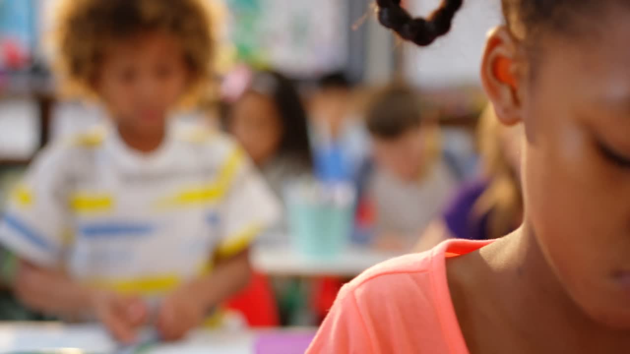 vista frontal de escolares de raza mixta dibujando en un cuaderno en el aula 4k