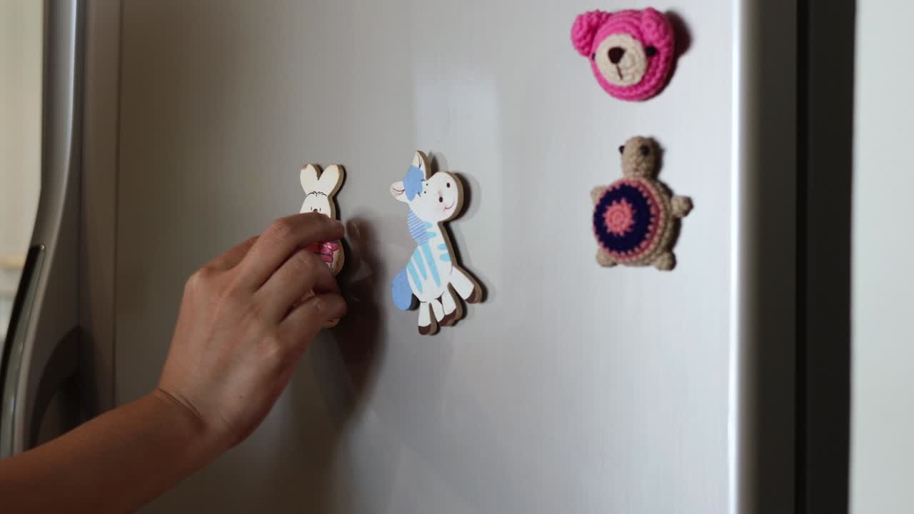 냉장고 문에 자석 장난감을 손으로 애니메이션합니다.