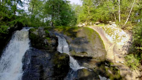 rising aerial footage showing a fresh water cascade flowing through the rocks in the middle of dense forest