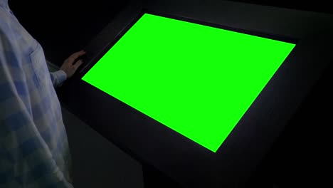 concepto de pantalla verde - mujer mirando un quiosco de exhibición verde en blanco en la exposición