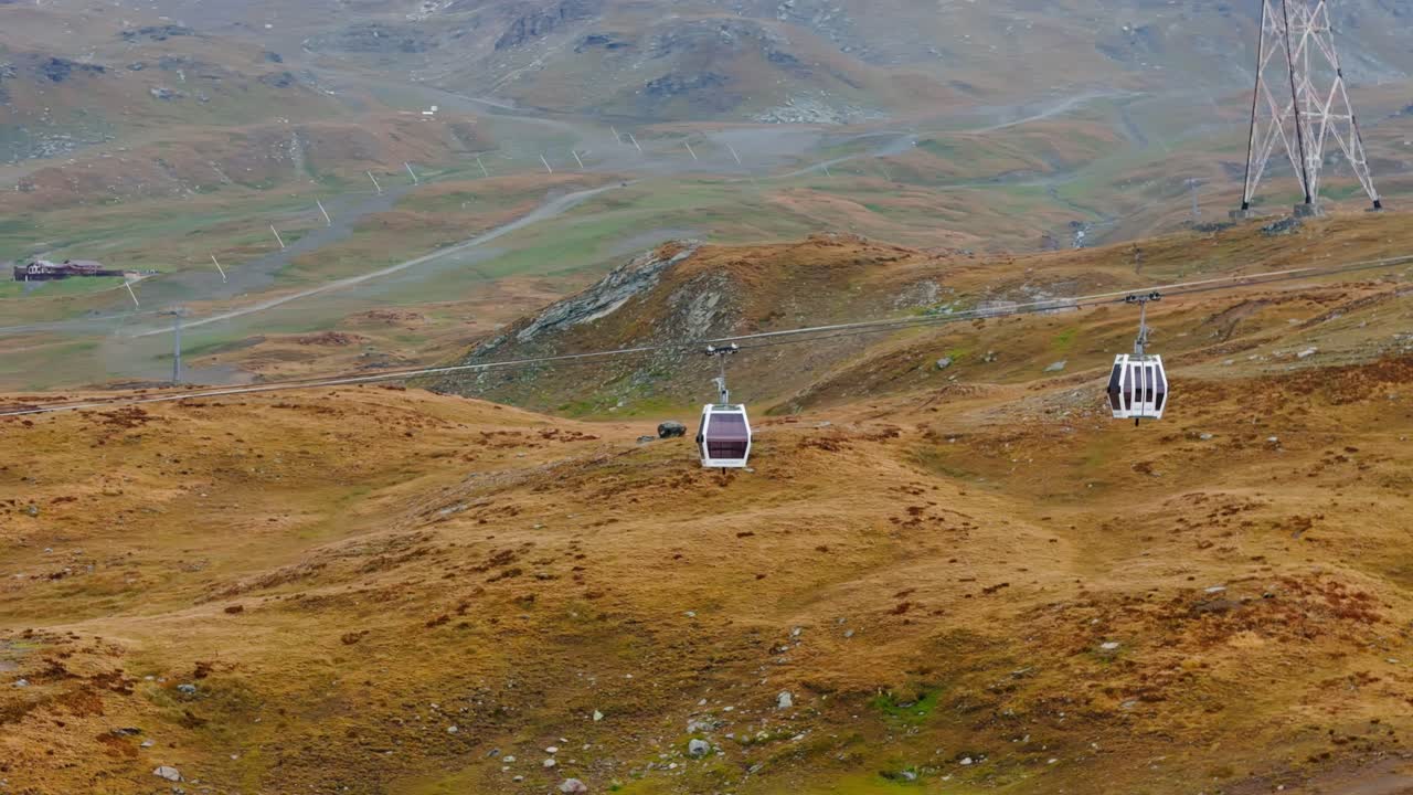 Aerial static drone shot showing cable cars standing still against a beautiful golden landscape in Cervinia, Italy, surrounded by alpine mountains