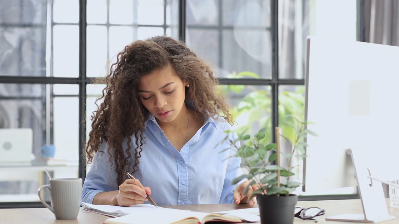 Young Woman Working and Writing at Her Modern Office Desk