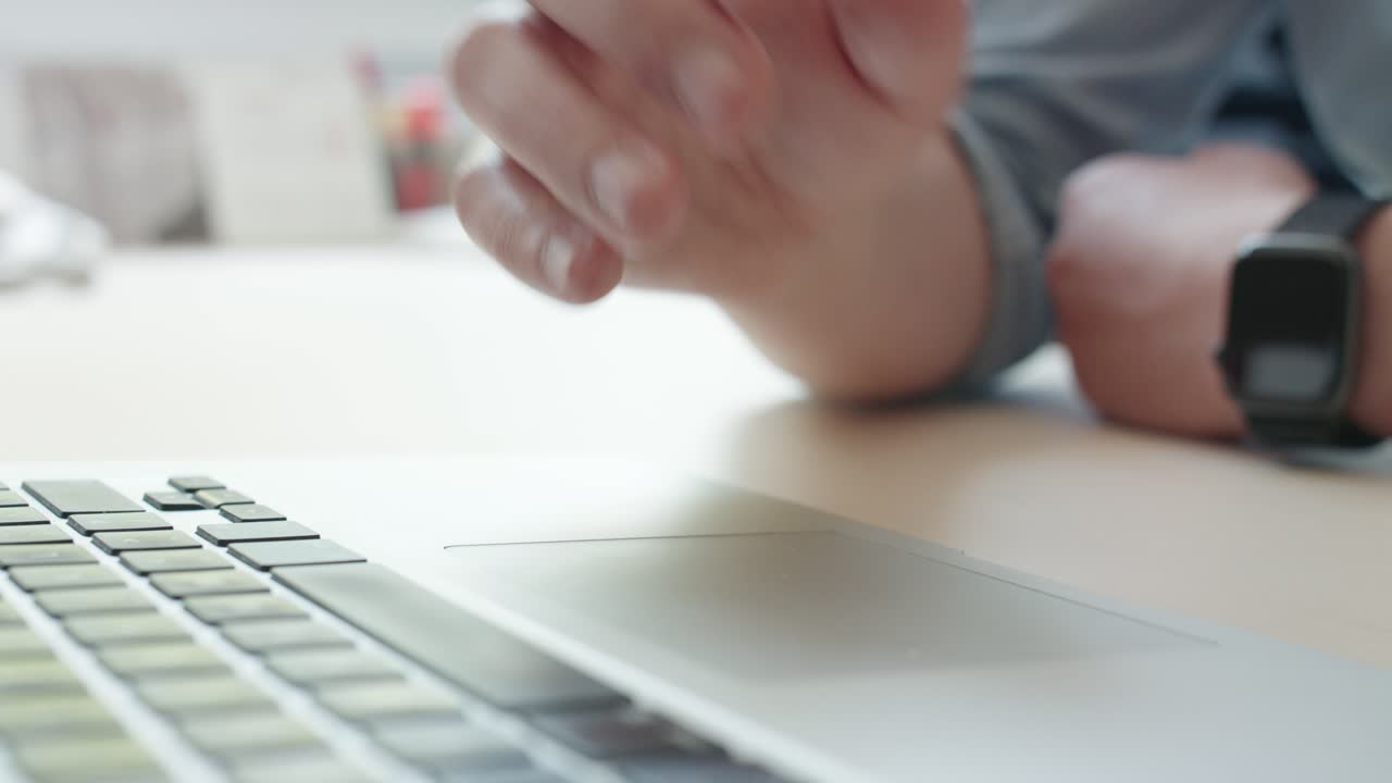 A close-up shot of a man's hand using the touchpad on a laptop. His fingers scroll, tap, and navigate, representing modern work, business, and Browse technology