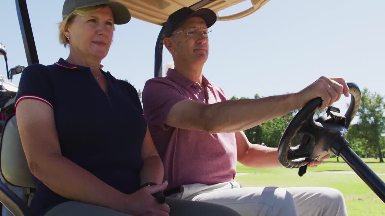골프 코스에서 골프 카트를 타고 뒤에 클럽을  ⁇ 고 있는 백인 수석 부부