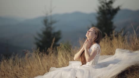 beautiful bride in a white dress posing in a field with mountains in the background