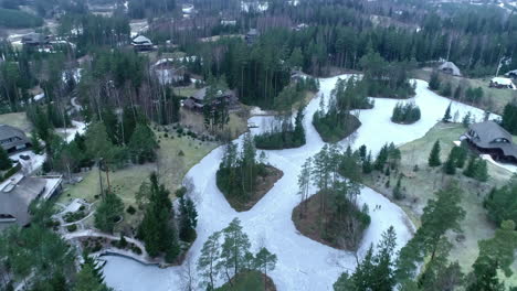 sobrevuelo aéreo lago congelado en el parque amatciems con bosques en invierno
