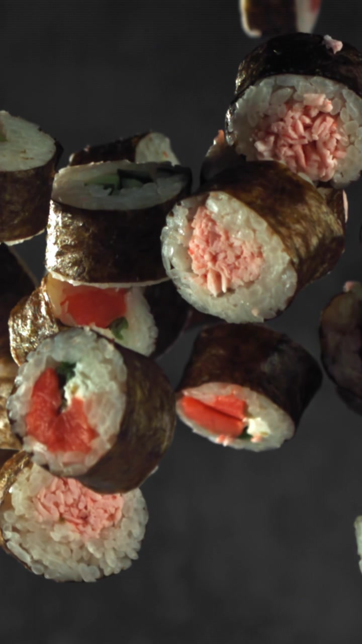 Roll di sushi giapponese freschi che fluttuano su uno sfondo scuro