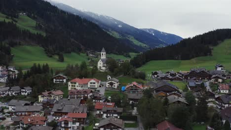 aereai video taken with dji mavic 2 pro of a small town in trentino alto adige with a church in the middle, the video shows the small town and the mountains in the background