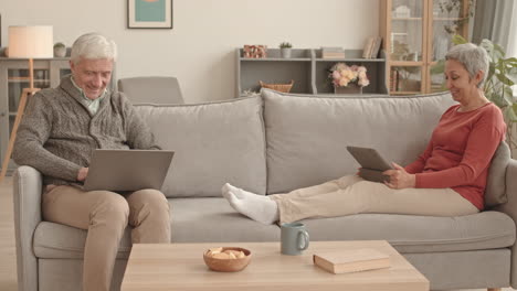 older couple relaxing on a sofa using technology