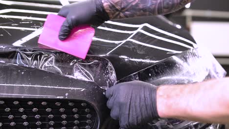hombre que cubre el coche con cinta de poliuretano de vinilo. películas para el coche. pegatina película protectora en el coche