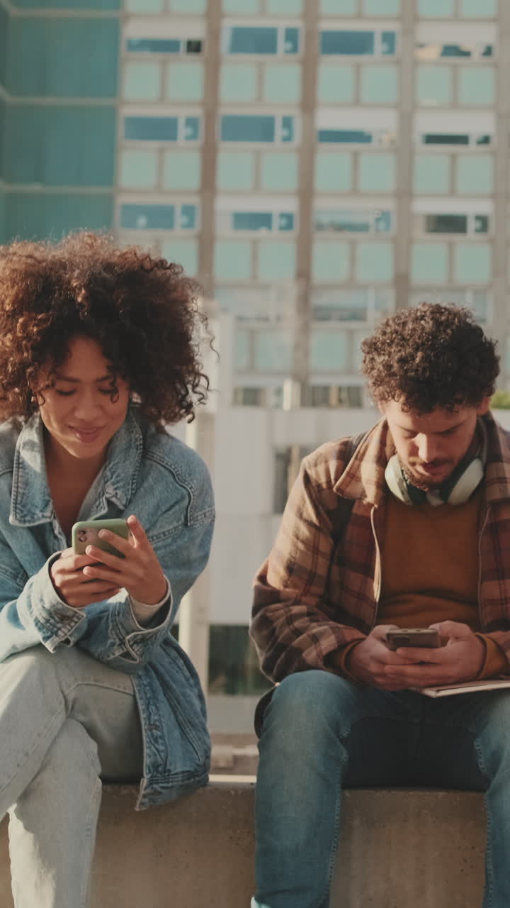 To unge voksne bruger mobiltelefoner udendørs