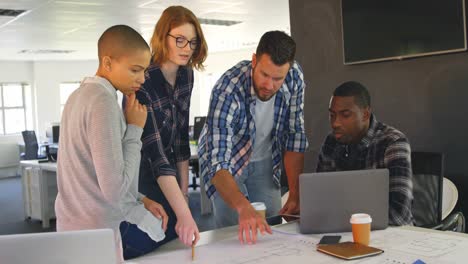 Young-nixed-race-business-team-discussing-over-blueprint-in-modern-office-4k