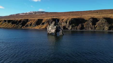 drone shot of hvitserkur rock formation on water in iceland during winter