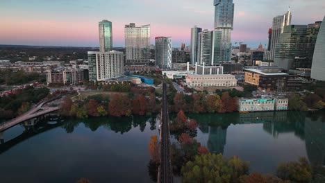 Pfluger-Fußgängerbrücke-Und-Eisenbahn-Mit-Skyline-Der-Stadt-über-Den-Lady-Bird-Lake-In-Der-Innenstadt-Von-Austin,-Texas