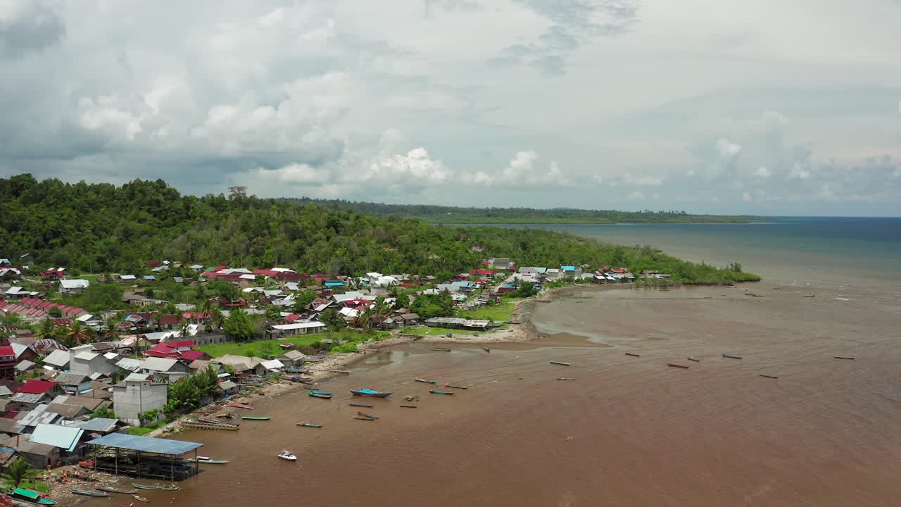 Aerial flight above local Mentawai fishing village in murky ocean bay